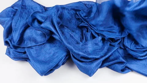 Blue silk fabric falls slowly in slow motion onto a clean white background. Stock Footage 337403335
