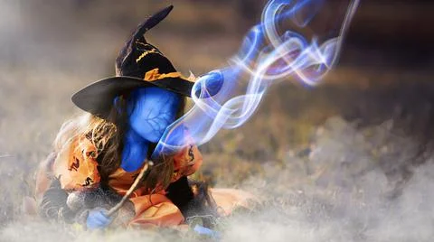 Blue skinned witch without face conjures magic wand, creepy halloween background Stock Photos