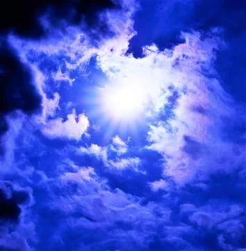 The blue sky and bright rays of the sun Shine through the fluffy clouds. Stock Photos