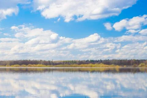 Blue sky and clouds reflected in the river. Ripples on the surface of the wat Stock Photos