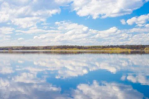 Blue sky and clouds reflected in the river. Ripples on the surface of the wat Stock Photos