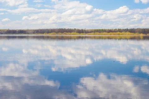 Blue sky and clouds reflected in the river. Ripples on the surface of the wat Stock Photos