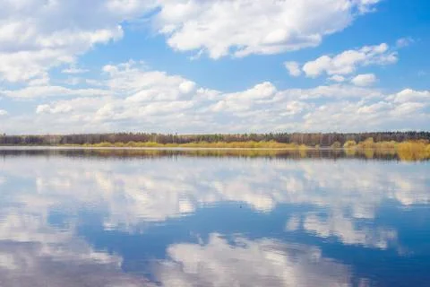 Blue sky and clouds reflected in the river. Ripples on the surface of the wat Stock Photos