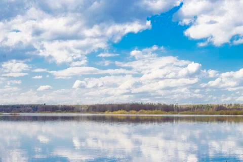 Blue sky and clouds reflected in the river. Ripples on the surface of the wat Stock Photos