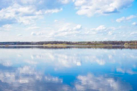 Blue sky and clouds reflected in the river. Ripples on the surface of the wat Stock Photos
