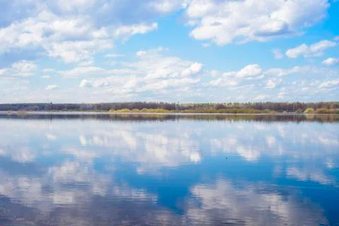 Blue sky and clouds reflected in the river. Ripples on the surface of the wat Stock Photos