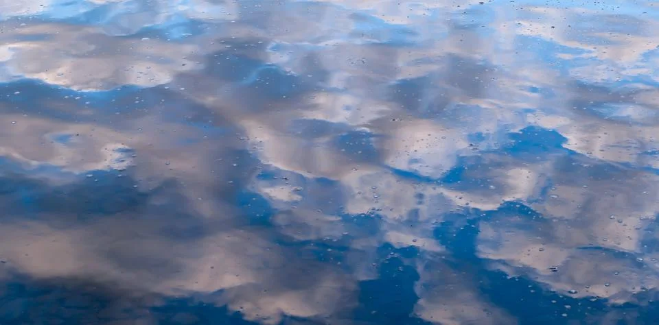 Blue sky and clouds reflected upon water Stock Photos