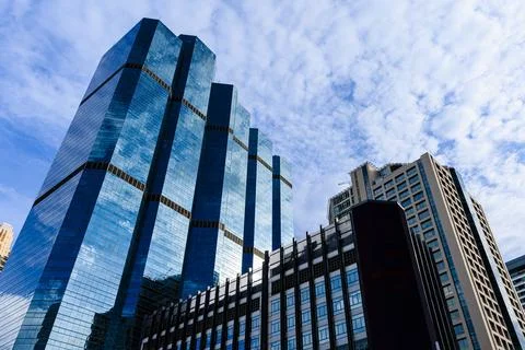 Blue sky and clouds reflected on the glass of office business buildings in .. Stock Photos