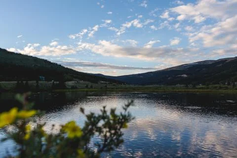Blue sky and clouds at sunset reflecting over a mountain lake in Colorado Stock Photos