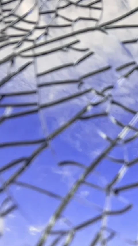 Blue sky and clouds through cracked glass as camera moves downward Video stock 316329770