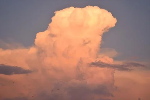 Blue sky and a large cloud with the colors of the sunset Stock Photos