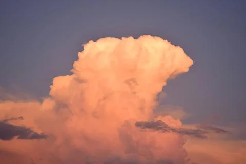 Blue sky and a large cloud with the colors of the sunset Stock Photos