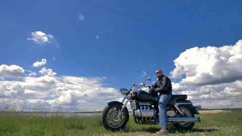Blue sky and white clouds, a biker and his motorcycle. Stock Footage 77750778