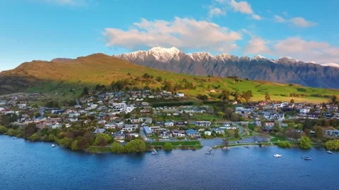 Blue sky and white clouds, snow-capped mountain peaks, lakeside town buildings Stock Footage 257653905