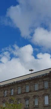 Blue sky and white clouds over European building with emergency speakers Stock Photos