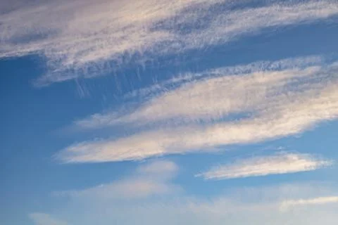 Blue sky background with tiny stratus cirrus striped clouds. Clearing day and Stock Photos