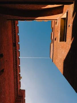Blue sky between red brick defensive walls. Low angle view of airplane contrail Stock Photos