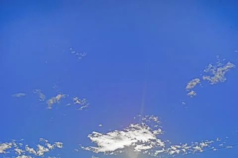 Blue sky with clouds against the sun in the background Stock Photos