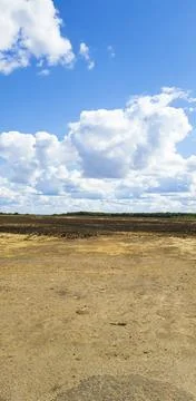 Blue sky with clouds on the background of a field and a dirt road Stock Photos
