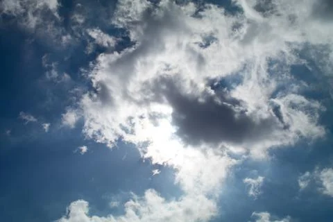 Blue sky with clouds covering the sun Stock Photos