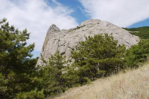 Blue sky with clouds lying on a small mountain cliff Stock Photos