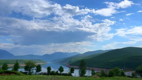 Blue sky with clouds over green hills and distant mountains Stock Footage 310246786