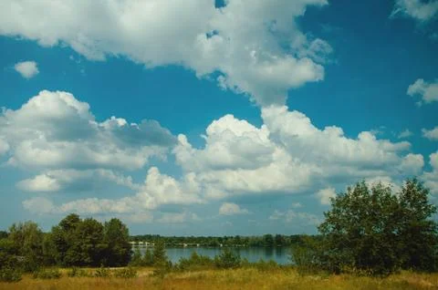 Blue sky with clouds, river and trees on the riverbank. Stock Photos