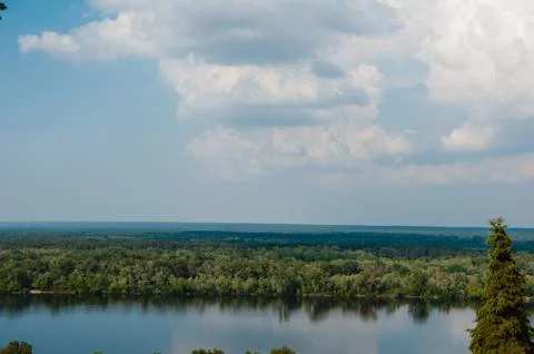 Blue sky with clouds, river and trees on the riverbank. Foto stock