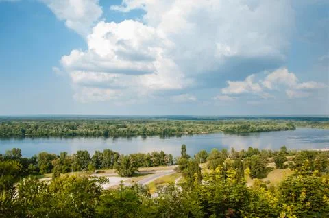 Blue sky with clouds, river and trees on the riverbank. Stock Photos
