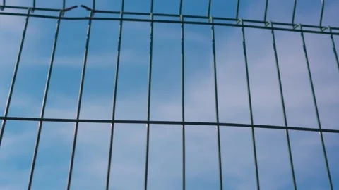 Blue sky with clouds through metal mesh fence. Stock Footage 249654030