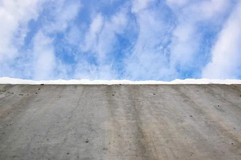 Blue sky with clouds visible from the top of snow and concrete surface Foto stock