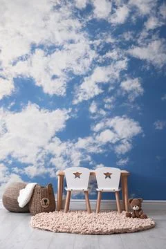 Blue sky with clouds as wallpaper pattern. Baby room interior with table an.. Stock Photos
