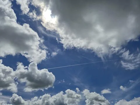 Blue sky with dramatic clouds and contrails Stock Photos