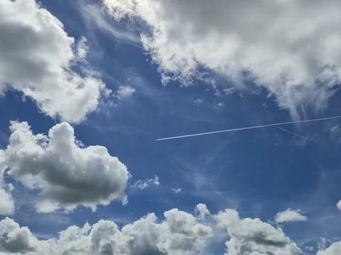 Blue sky with dramatic clouds and aircraft contrail Stock Photos
