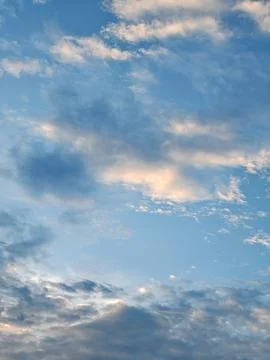Blue sky filled with dramatic clouds at sunset with peach and gold highlight Stock Photos
