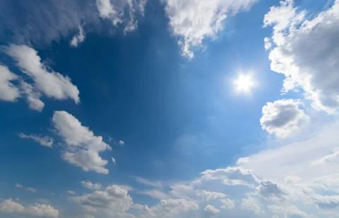 Blue sky with fluffy clouds and sun Stock Photos