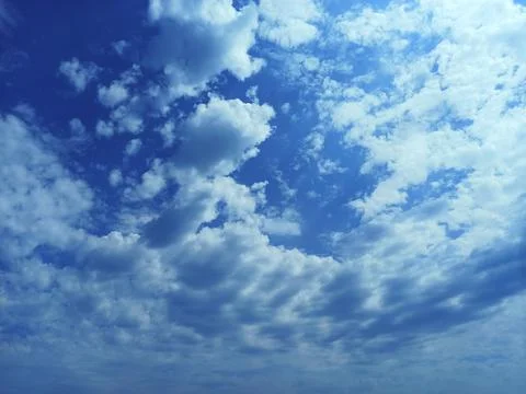Blue sky with fluffy clouds. The sun shines through the clouds Stock Photos