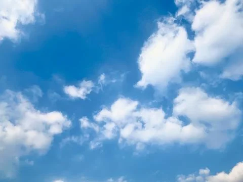 Blue sky with fluffy white clouds scattered across the horizon on a bright sunny Stock Photos