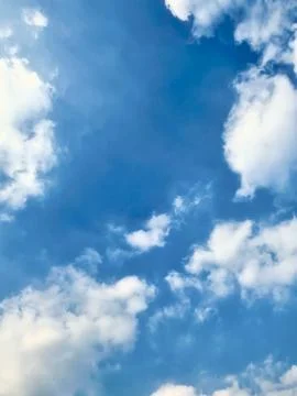 Blue sky with fluffy white clouds scattered across the horizon on a bright sunny Stock Photos