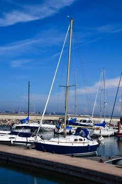 Blue sky frames boats at calm harbor Stock Photos