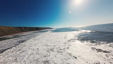 Blue sky glows above ocean waves crashing toward shore Stock Footage 339803691