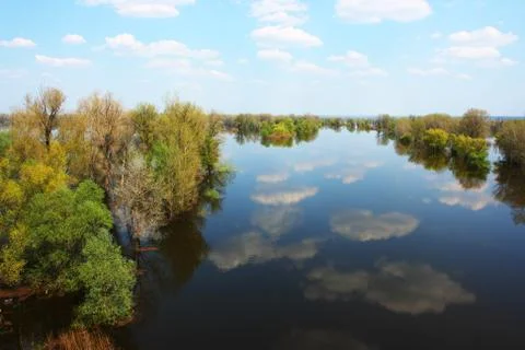Blue sky with heap clouds reflecting in the flooded river Stock Photos