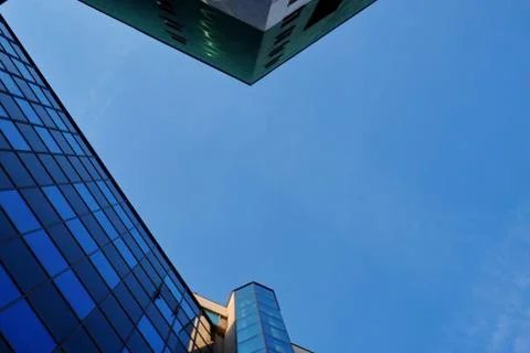 Blue sky with light small clouds between skyscrapers in the city on a Sunny c Stock Photos
