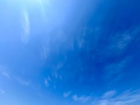 Blue sky with light soft wispy cirrus clouds on a bright sunny day background Stock Photos