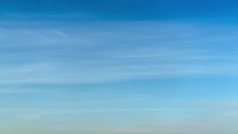 Blue sky with light wispy clouds spanning the horizon, time lapse. Clear weather Stock Photos