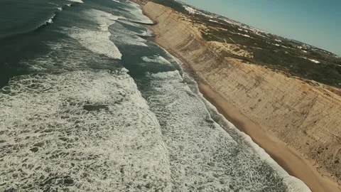 Blue sky meets rugged cliffs beside crashing waves Stock Footage 339789420