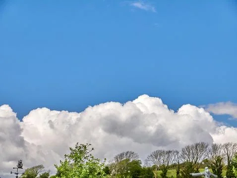 Blue sky over dramatic white clouds above trees 스톡 사진