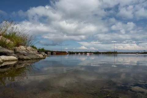 A blue sky with patchy clouds over a calm bay in summertime. From the swedish Stock Photos