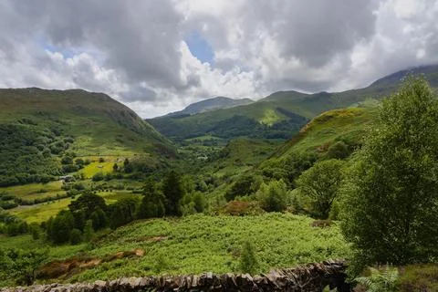 Blue sky peeps through the dark clouds above the hills and valleys in Eryri.. Foto stock