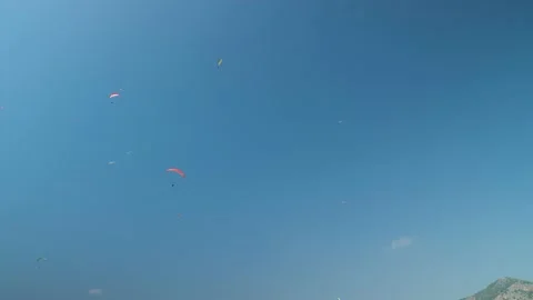 The blue sky provides the perfect backdrop for paragliders as they soar Stock Footage 231764558